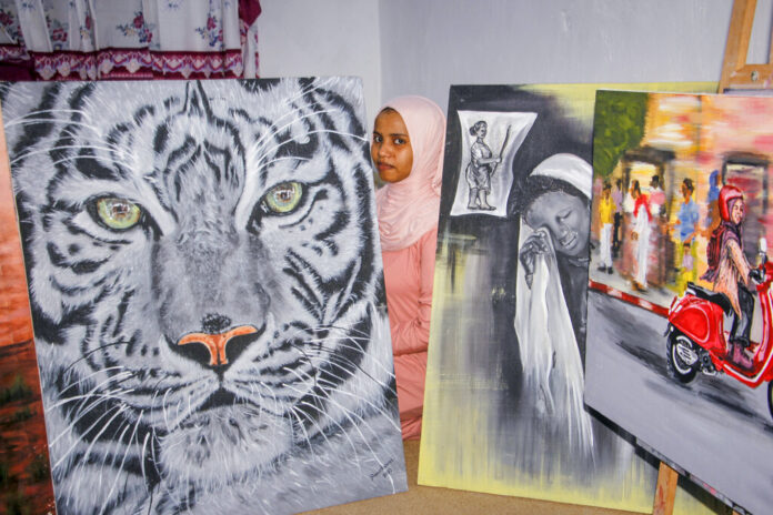 A Somali artist stands with her art, a painting of a white tiger