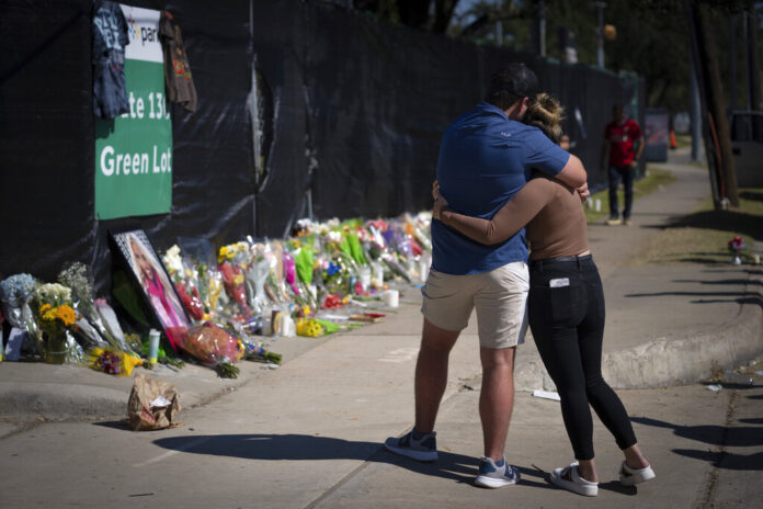 Two people hug in front of a memorial set up for victims of the Astroworld tragedy,