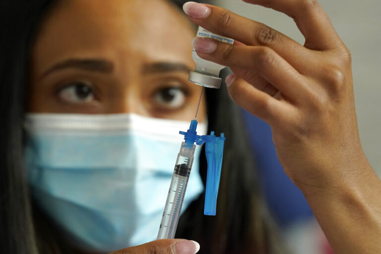 A nurse fills a syringe with a COVID-19 booster dose of the vaccine